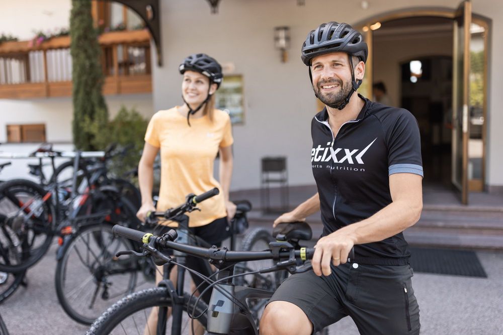 Zwei Radfahrer mit Helm stehen lächelnd neben ihren Fahrrädern