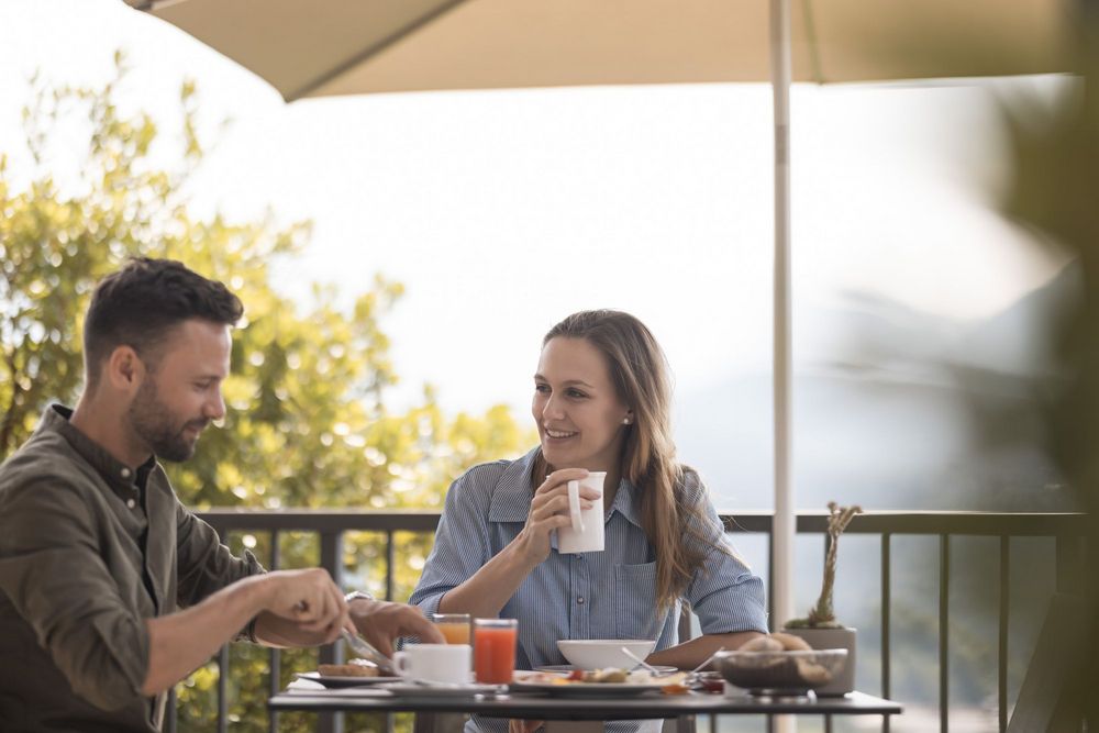 Paar genießt Frühstück auf Terrasse unter Sonnenschirm