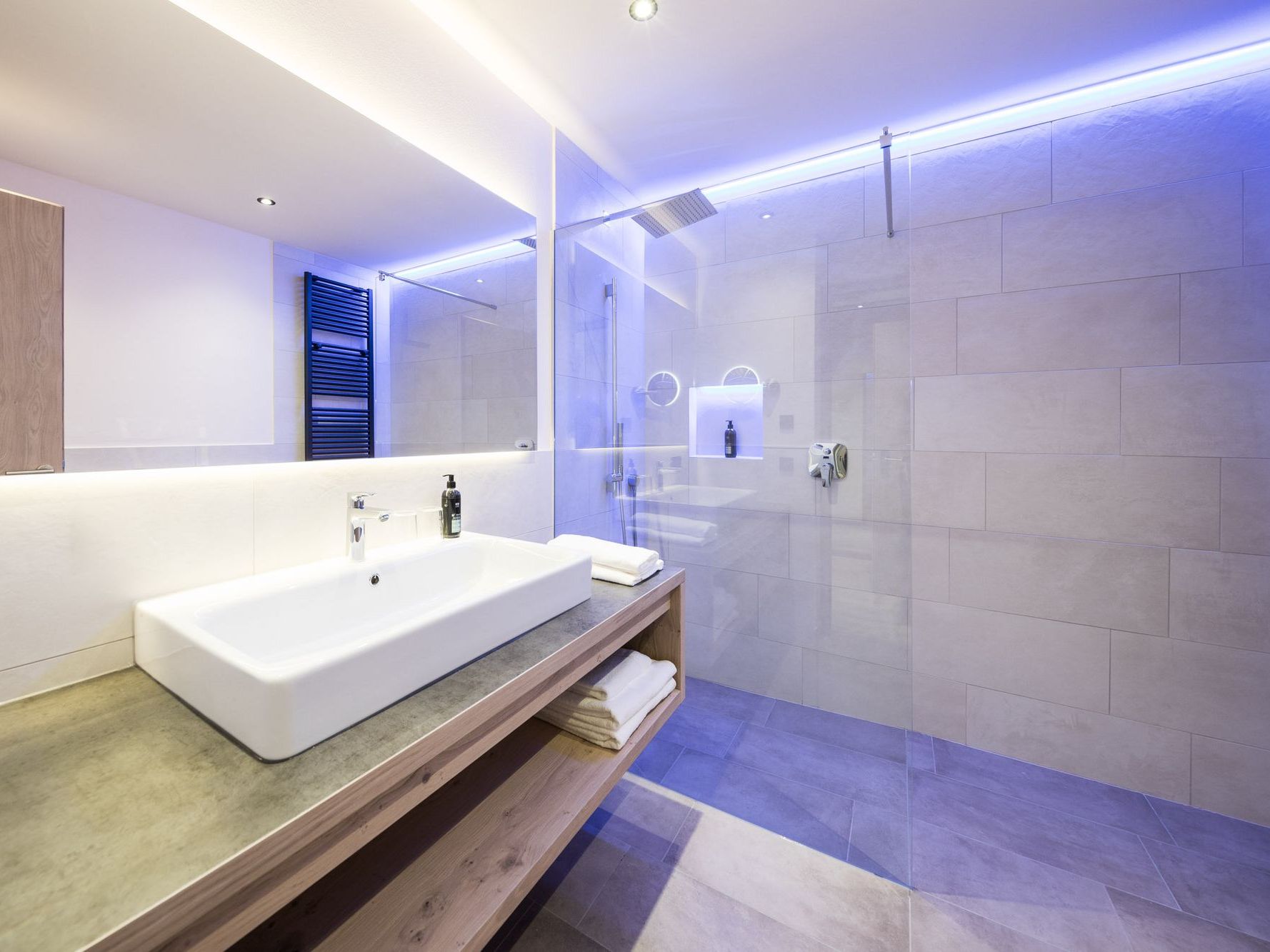 Modernes Badezimmer mit Waschbecken, Spiegel und beleuchteter Dusche