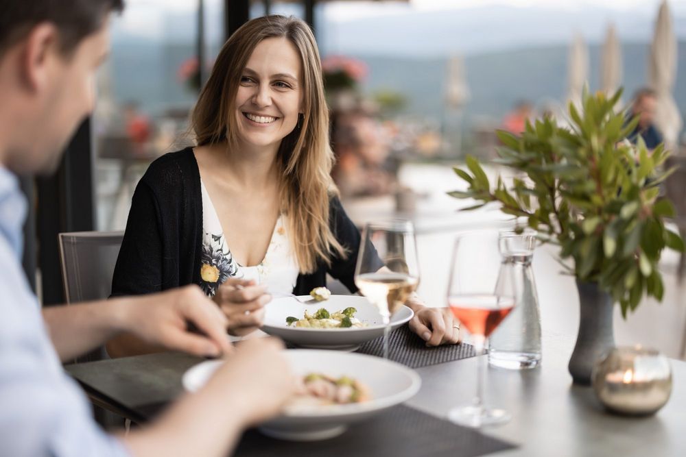 Lächelnde Frau beim Essen in einem Restaurant mit einem Mann am Tisch.