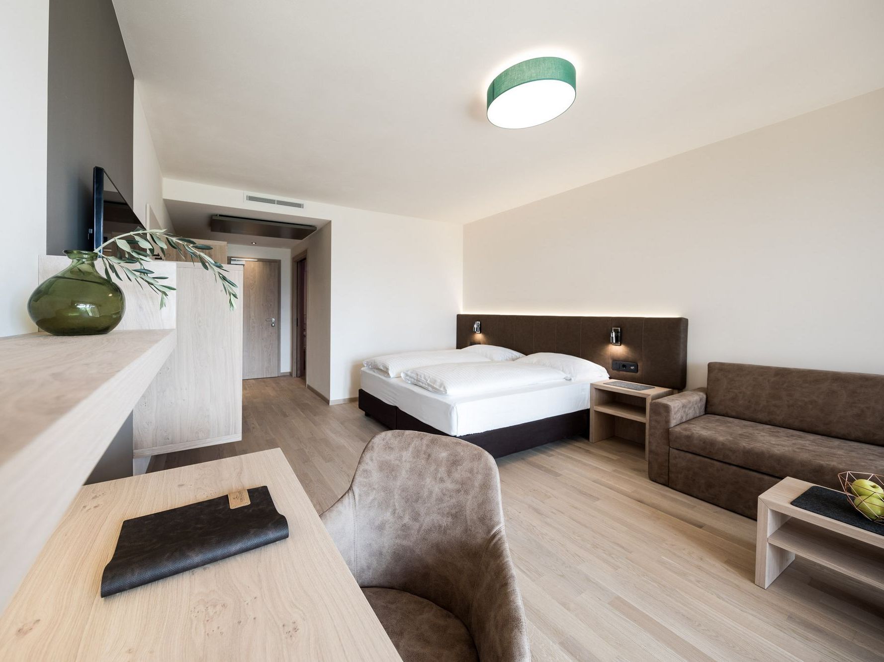Modernes Hotelzimmer mit Doppelbett, Sofa und Schreibtisch