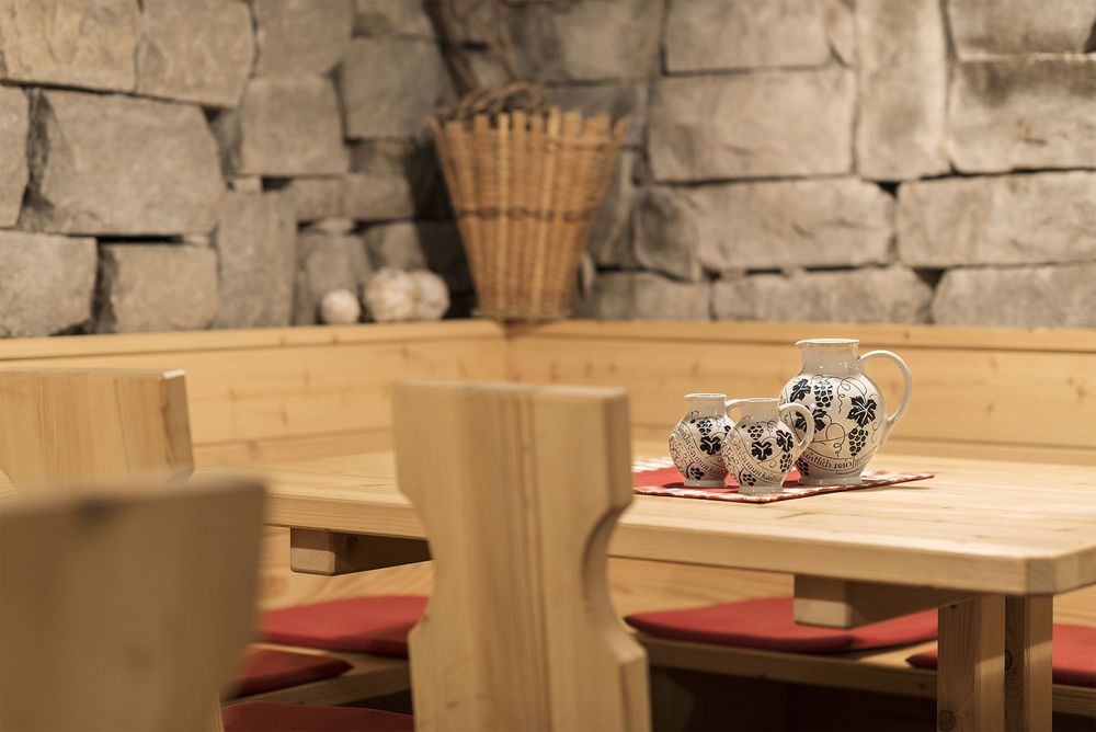 Gemütliche Holzecke mit Steinhintergrund und drei dekorativen Krügen auf dem Tisch