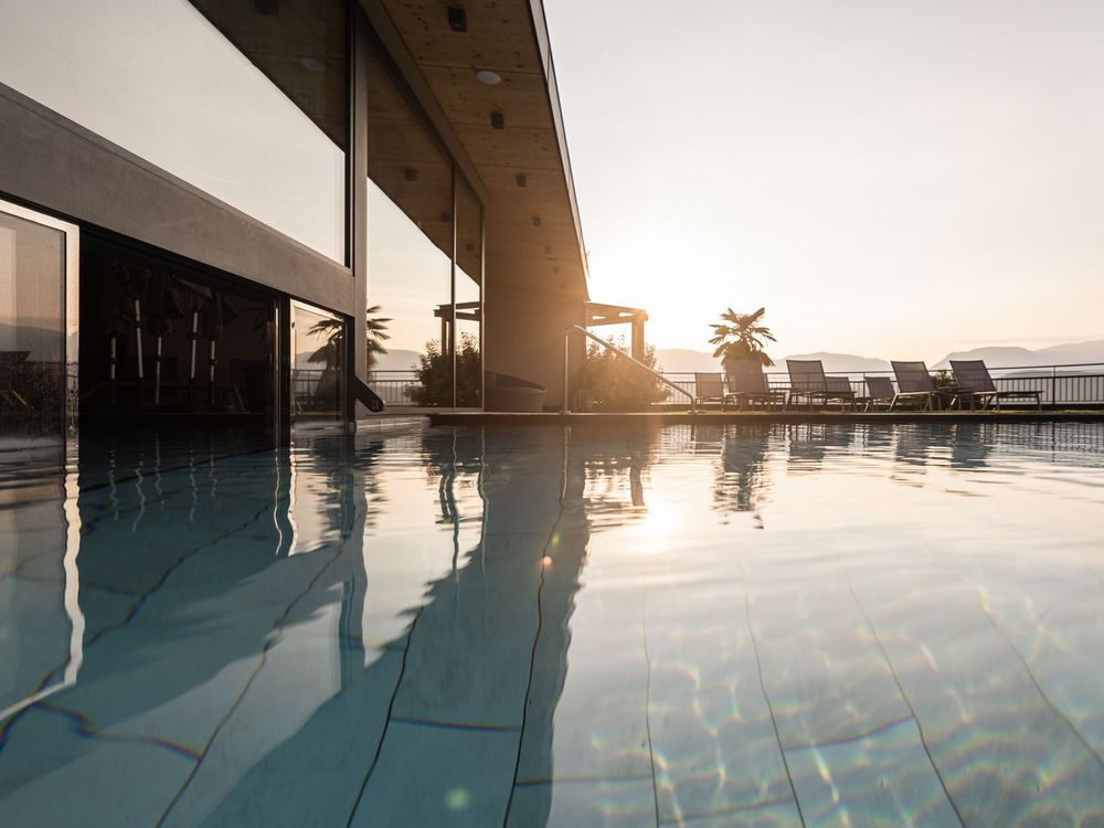 Schwimmbad mit Liegestühlen bei Sonnenuntergang