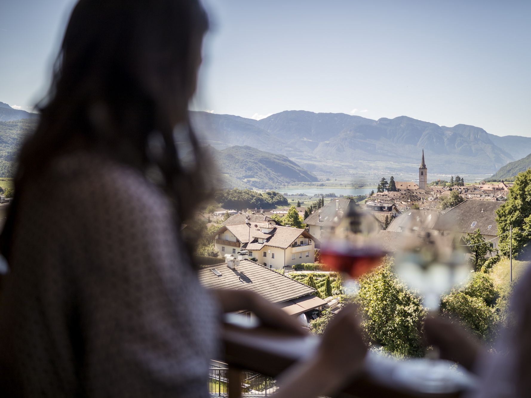 Zwei Personen mit Wein vor einem malerischen Dorf und Bergen