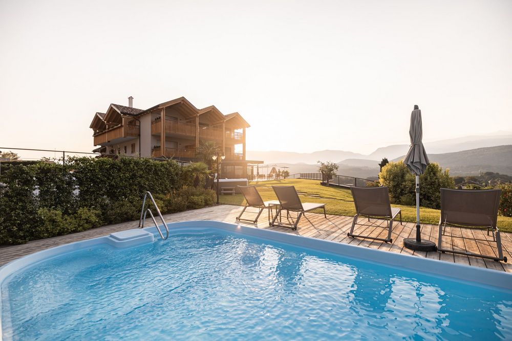 Schwimmbad mit Liegestühlen und Haus im Hintergrund bei Sonnenuntergang