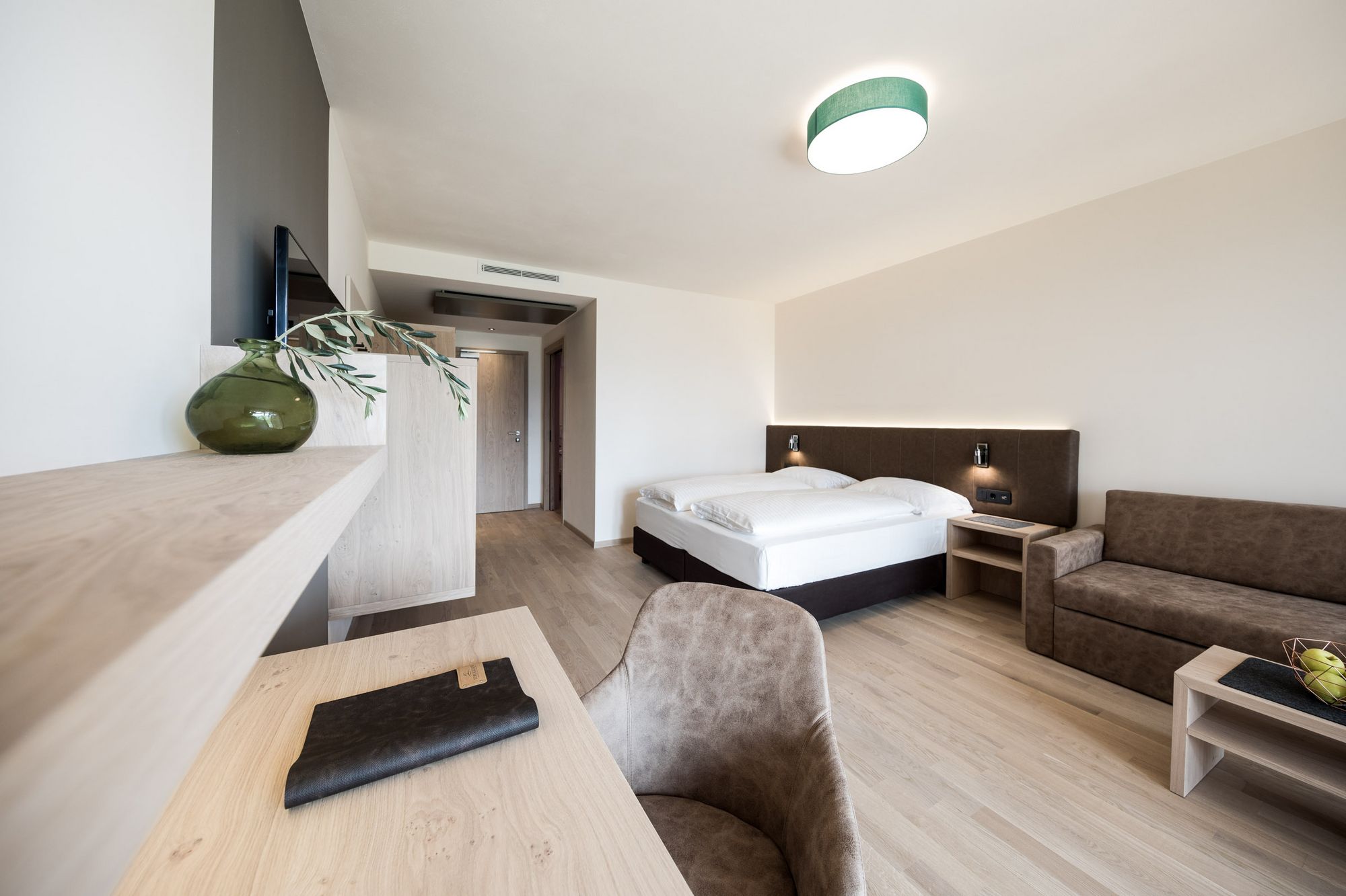 Modernes Hotelzimmer mit Doppelbett, Sofa und Schreibtisch
