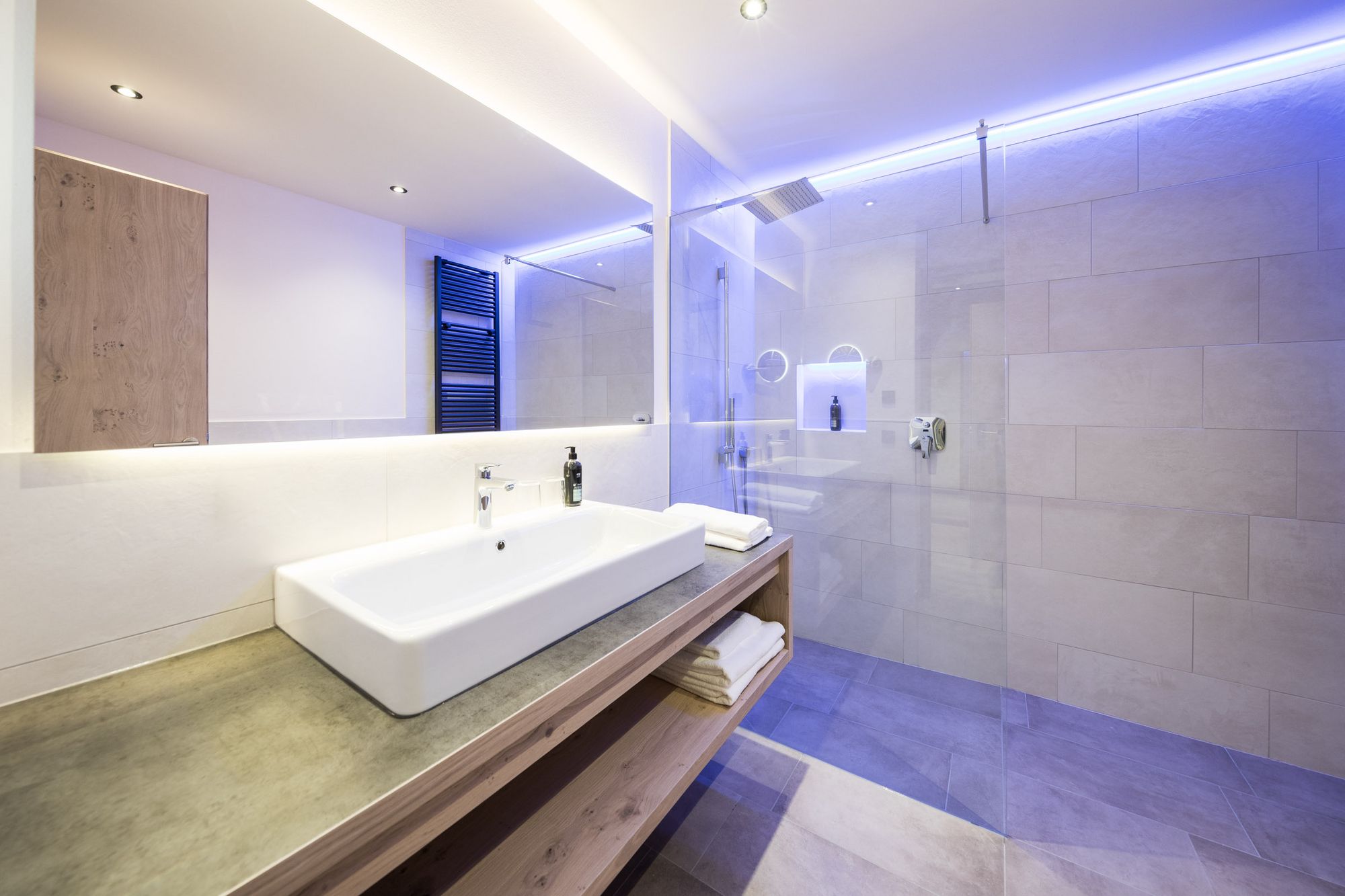 Modernes Badezimmer mit Waschbecken, Spiegel und beleuchteter Dusche