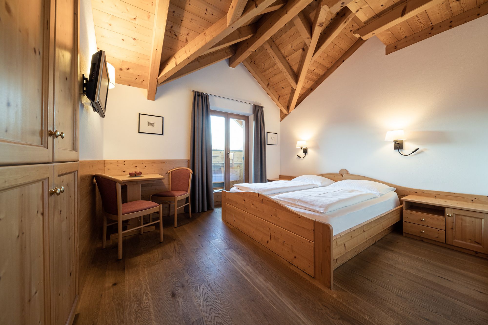 Gemütliches Schlafzimmer mit Holzmöbeln, Holzboden und sichtbaren Dachbalken