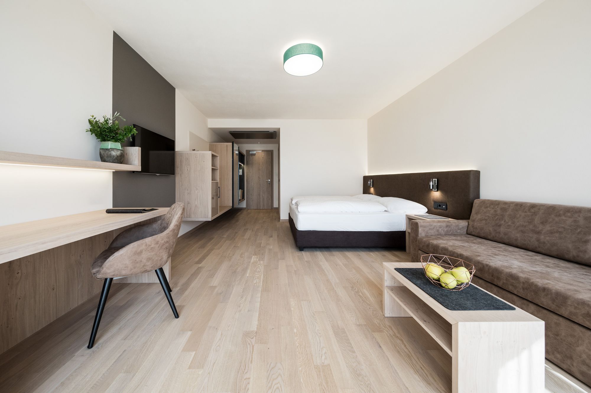 Modernes Hotelzimmer mit Doppelbett, Sofa und Schreibtisch